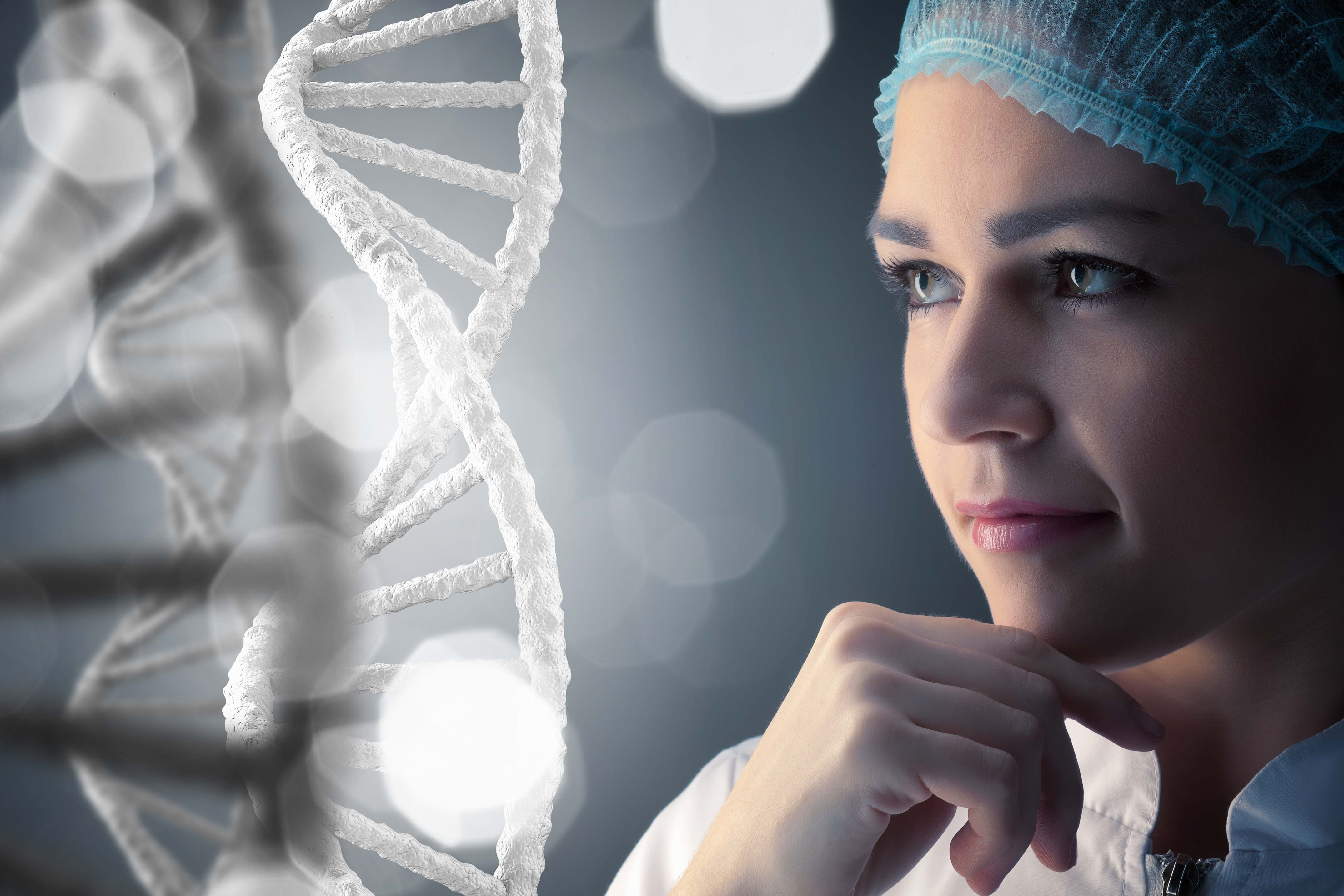 Kvinne i laboratorieutstyr som ser på en DNA-struktur.